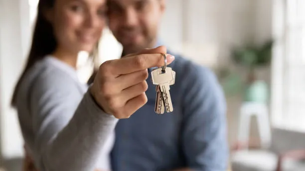 Una ejecutiva entrega las llaves de su nueva vivienda a una pareja